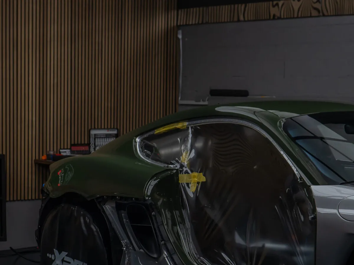 Facharbeiter bei der Installation einer farbigen Lackschutzfolie am Porsche 718 GT4 RS bei BespokeOne